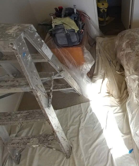 Cropped original photo showing a stepladder, tool bag and protective floor and furniture coverings